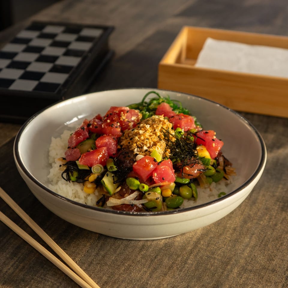 Hana Poke bowl with tuna, edamame, corn, seaweed, and rice, with chopsticks nearby.